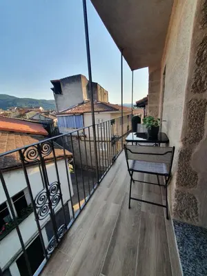 a balcony with a table and a chair on a building at A casa do Xastre in Allariz