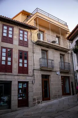 a building with red windows and a balcony at A casa do Xastre in Allariz