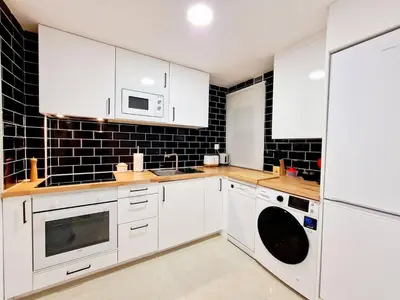 a kitchen with white appliances and black tiles at Apartamento Puente Romano in Ourense