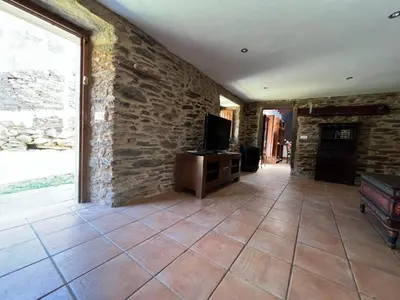a living room with a tv and a stone wall at Casal de Pedra in Santa Irene