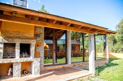 a house with a stone fireplace in the yard at Lagunas de Sanabria in Trefacio
