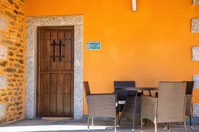a table and chairs in front of a building with a door at Lagunas de Sanabria in Trefacio