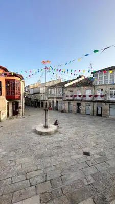a large courtyard with buildings and a street with flags at Celanova House in Celanova