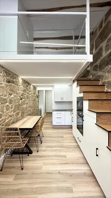 a kitchen with a table and a stone wall at Celanova House in Celanova