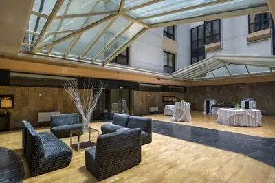 a lobby with chairs and tables and a glass ceiling at Exe Auriense in Ourense