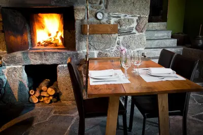 a wooden table in front of a fireplace at Fervenza Casa Grande & Restaurante in Reguengo