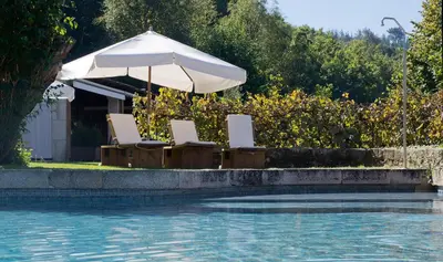 two chairs and an umbrella next to a swimming pool at Fervenza Casa Grande & Restaurante in Reguengo