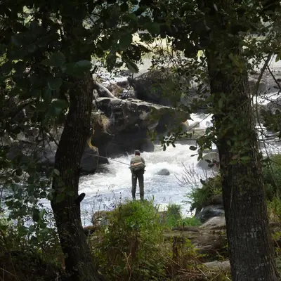 a man standing in the river looking at the water at Fervenza Casa Grande & Restaurante in Reguengo