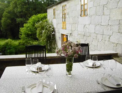 a table with plates and a vase of flowers on it at Fervenza Casa Grande & Restaurante in Reguengo