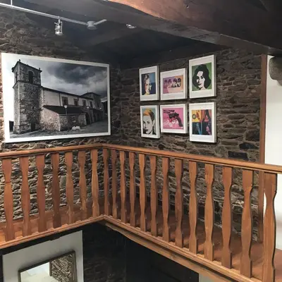 a wall of pictures on a staircase in a house at A Casacuberta in Marquiño