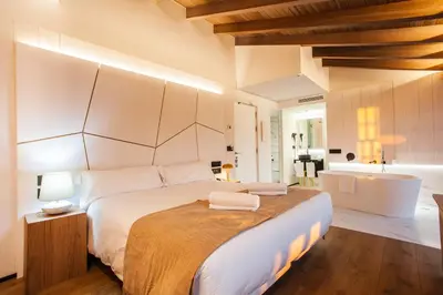 a bedroom with a large white bed and a bathroom at Hotel Plaza Obradoiro by Bossh! Hotels in Santiago de Compostela