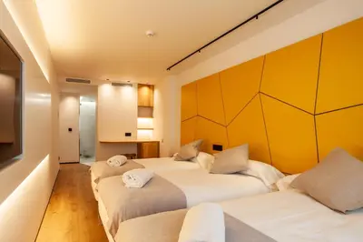 two beds in a room with yellow walls at Hotel Plaza Obradoiro by Bossh! Hotels in Santiago de Compostela