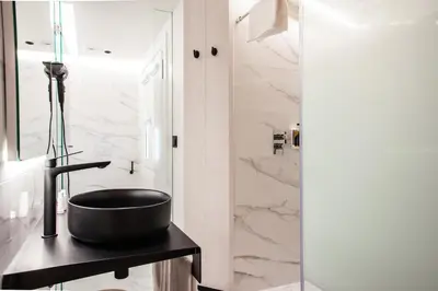 a bathroom with a black sink and marble walls at Hotel Plaza Obradoiro by Bossh! Hotels in Santiago de Compostela