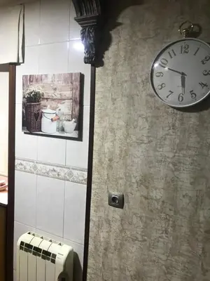 a clock on a wall with a picture and a radiator at Apartamento Cervantes in Ourense