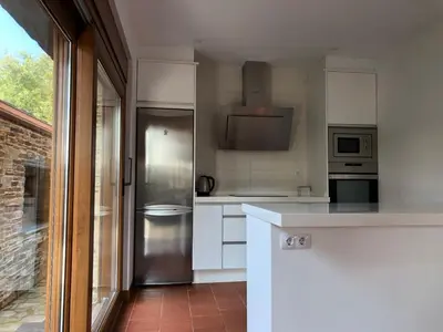 a kitchen with white cabinets and a stainless steel refrigerator at Apartamentos Montemar in Navia