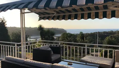 a patio with an umbrella and a chair on a balcony at Apartamentos Montemar in Navia