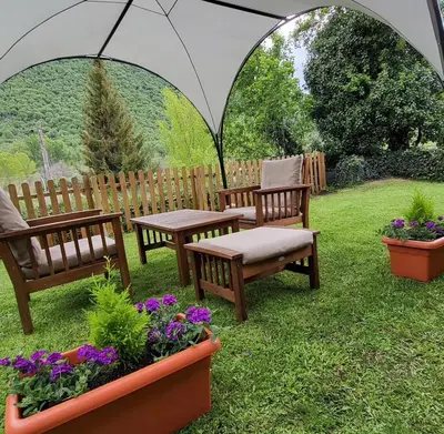 a patio with benches and flowers in the grass at Hotel Rural LA CÁRCEL in Murias de Paredes