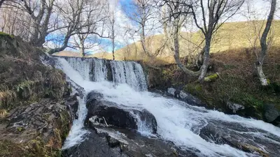 a waterfall on the side of a hill with trees at Hotel Rural LA CÁRCEL in Murias de Paredes