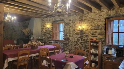 a dining room with tables and chairs and stone walls at Hotel Rural LA CÁRCEL in Murias de Paredes