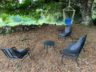 three chairs and a table and a swing under a tree at A Casa do Portal, tu casa rural en Campo Lameiro, cerca de Pontevedra in Campo Lameiro
