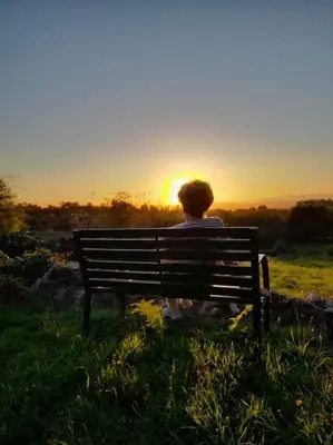 a person sitting on a bench watching the sunset at A Casa do Portal, tu casa rural en Campo Lameiro, cerca de Pontevedra in Campo Lameiro