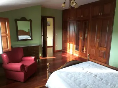 a bedroom with a bed and a chair and a mirror at Casa Rural A Telleira in A Estrada