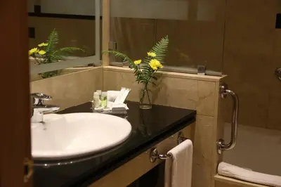 a bathroom with a sink and a vase of yellow flowers at Gran Hotel Los Abetos in Santiago de Compostela