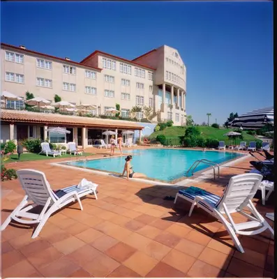 a swimming pool with two chairs and a building at Gran Hotel Los Abetos in Santiago de Compostela