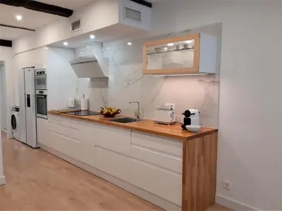 a kitchen with white cabinets and a wooden counter top at Apartamento con encanto en centro histórico Lugo -TineriaLucusHome in Lugo