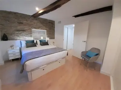 a bedroom with a large bed and a chair at Apartamento con encanto en centro histórico Lugo -TineriaLucusHome in Lugo