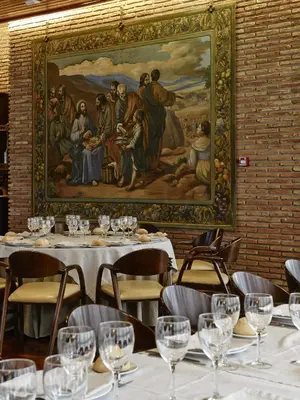 a painting hangs above a table in a restaurant at Hotel Alfonso IX in Sarria