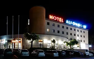 a hotel at night with cars parked in a parking lot at Hotel Alfonso IX in Sarria