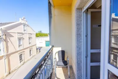 a balcony with a chair and a building at APARTAMENTOS RIAMAR 2 in Ribadeo