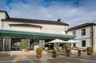 a building with tables and umbrellas in a courtyard at Hotel Palacio del Carmen, Autograph Collection in Santiago de Compostela