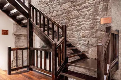 a set of wooden stairs in a room with a stone wall at Hotel Palacio del Carmen, Autograph Collection in Santiago de Compostela