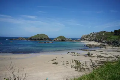 a beach with some rocks in the water at Casa Gayol in El Franco