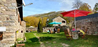 a patio with a table with a red umbrella and chairs at Posada El Rincón de Babia in La Cueta