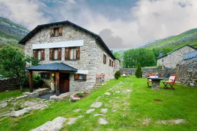 a stone house with a picnic table in front of it at Posada El Rincón de Babia in La Cueta