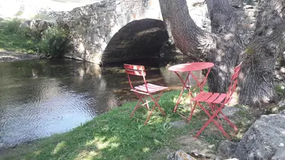 two red chairs and a table next to a river at Posada El Rincón de Babia in La Cueta