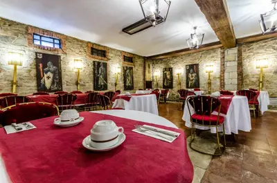 a dining room with tables and chairs with red table cloth at Hotel Temple Ponferrada in Ponferrada