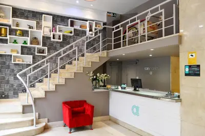 a stairway with a red chair in a lobby at Hotel Alda San Carlos in Santiago de Compostela