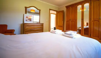 a bedroom with a white bed with a dresser and a mirror at Casa Olivar El Mandarino in Orazo