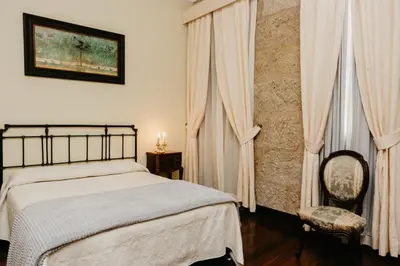 a bedroom with a bed and a chair and curtains at Pazo Almuzara in Boborás