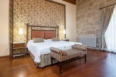 a bedroom with a large bed and a stone wall at Eurostars Monumento Monasterio de San Clodio Hotel in Leiro