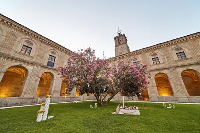 a building with a tree with pink flowers in front of it at Eurostars Monumento Monasterio de San Clodio Hotel in Leiro