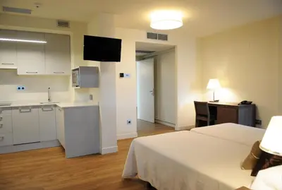 a room with a bed and a kitchen and a table at Guiana Rooms & Suites in Ponferrada
