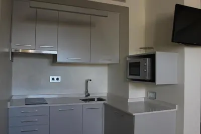 a kitchen with white cabinets and a microwave at Guiana Rooms & Suites in Ponferrada