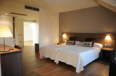 a bedroom with a large white bed and a desk at Guiana Rooms & Suites in Ponferrada