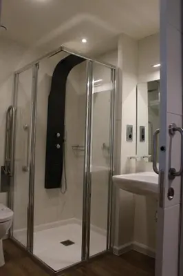 a shower with a glass door in a bathroom at Guiana Rooms & Suites in Ponferrada