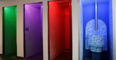 a bathroom with colorful stalls with a toilet in it at Hotel Spa Congreso in Teo